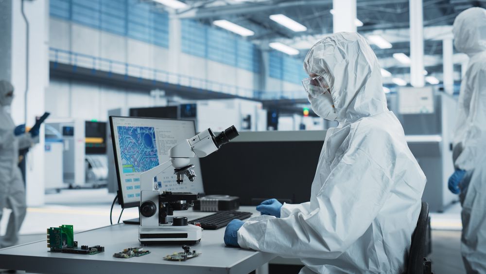 Unrecognizable people in protective gear working in front of screen with fluorescent lights