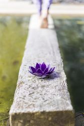 Aesthetic shot of a purple glass lotus while a woman walks away. Copy space