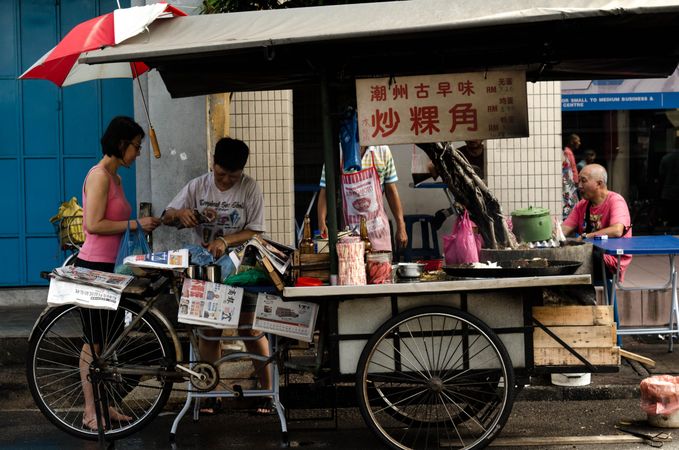 People buying snack at a street food cart in George Town, Penang, Malaysia