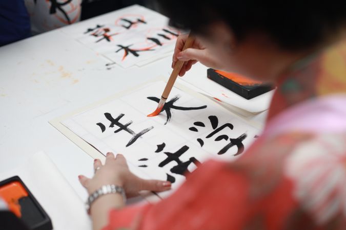 Back view of person writing Japanese on paper