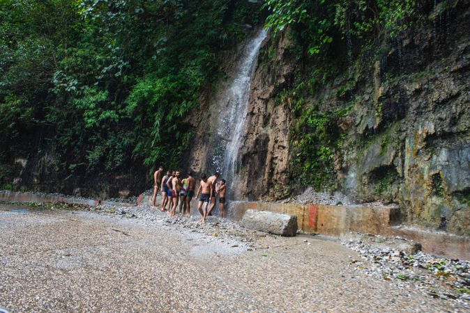 Group of Indian men in underwear bathing in waterfall on side of highway in Mussoorie India