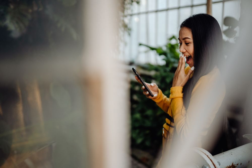 Charming long haired Asian woman browsing smartphone in botanical garden