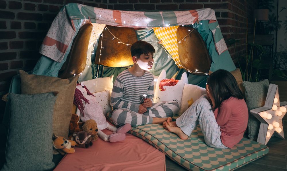Kid making terror gesture illuminated with lantern while little scared girl cover face with hands