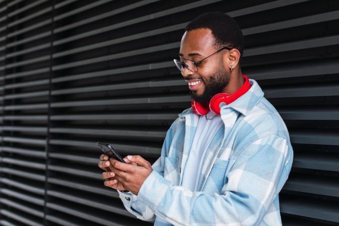 Cheerful Black man with smartphone listening to music