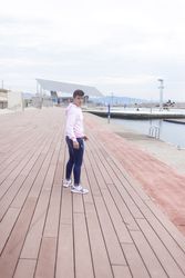 Young male teenager walking along rocky breakwater and looking back at camera