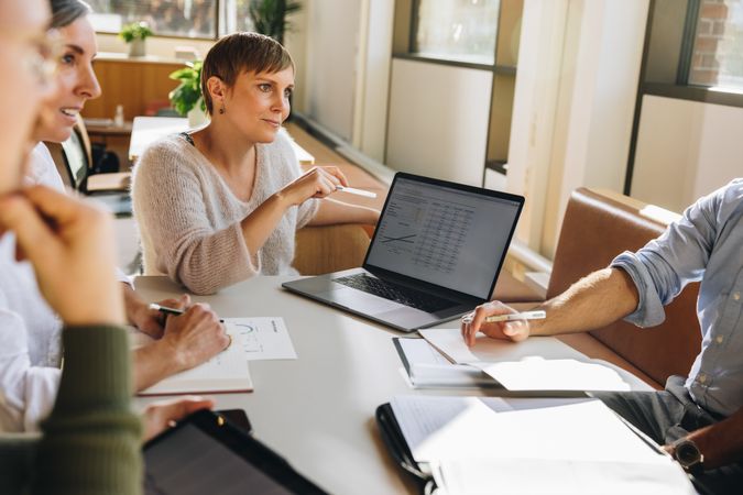 Businesswoman explaining financial details on laptop in meeting
