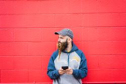 Man using smartphone near red wall