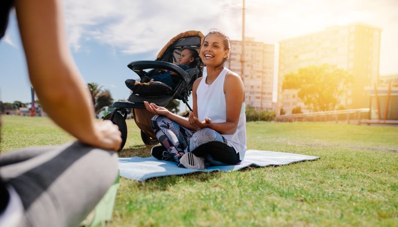 Active mothers doing yoga in park with baby in a stroller