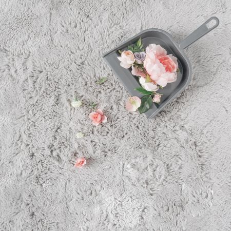 Dustpan and brush with flowers on grey carpet