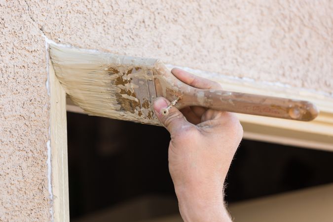 Professional Painter Cutting In With Brush to Paint House Door Frame.