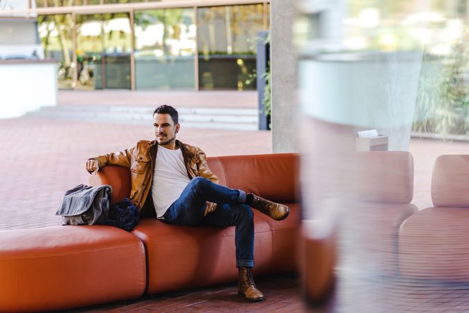 Stylish man sitting on red leather couch