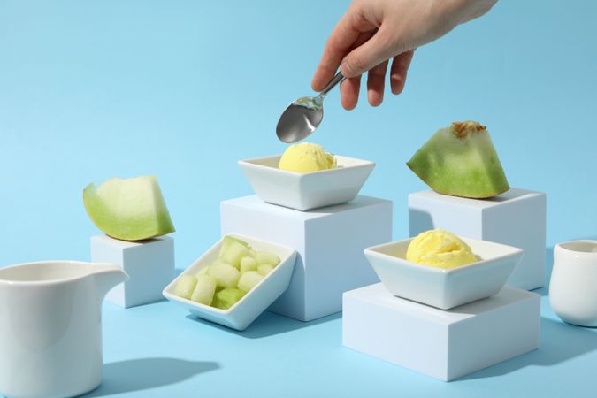 Ice cream scoops in a bowl with slices of fresh melon on a blue background