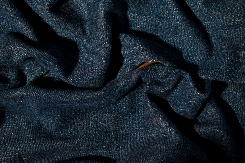 Close up detail crumpled wavy Navy blue jeans fabric background texture.