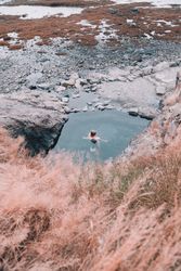 Woman in pond near hill on shore