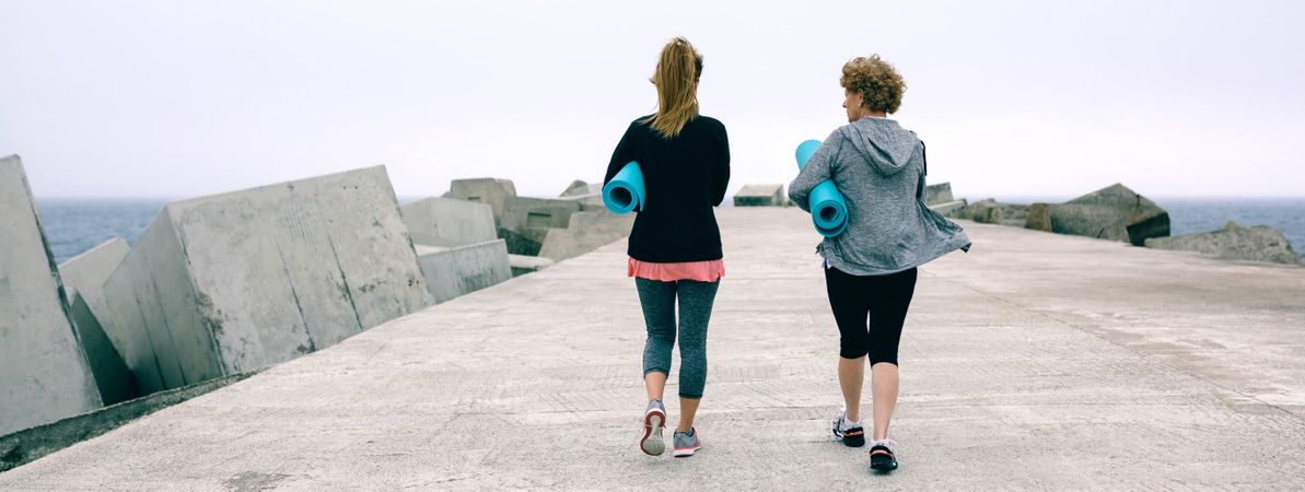 Back view of two women walking by sea pier