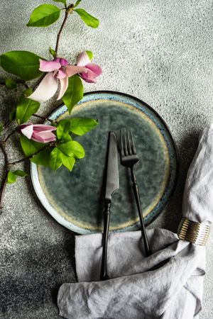 Floral scene with magnolia blooming on grey plate with napkin