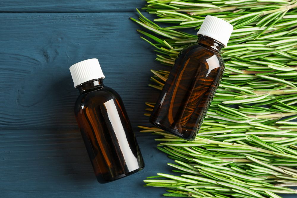 Rosemary oil and leaves on wooden background, space for text