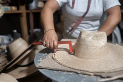 Cutting the brim of a traditional natural fiber hat