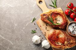 Composition with fried steaks and ingredients on gray background. Grilled food