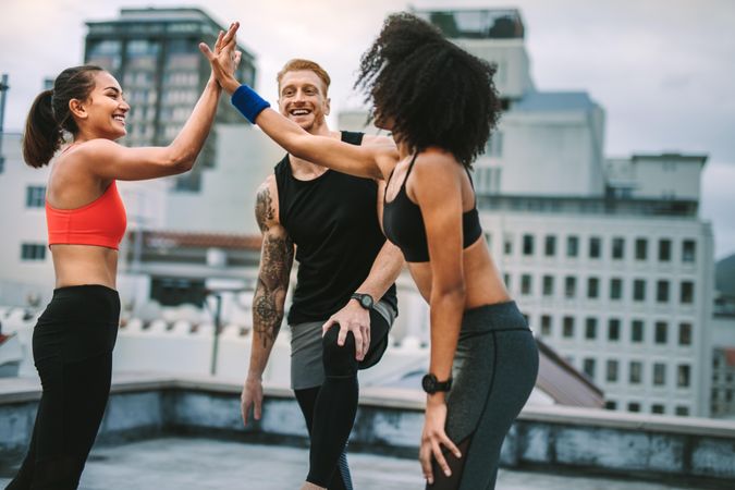 Fitness man and women relaxing and having fun after workout on rooftop