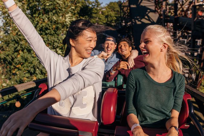 Shot of young friends enjoying and cheering on roller coaster ride