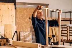 Bearded male with measuring table and furniture in shop