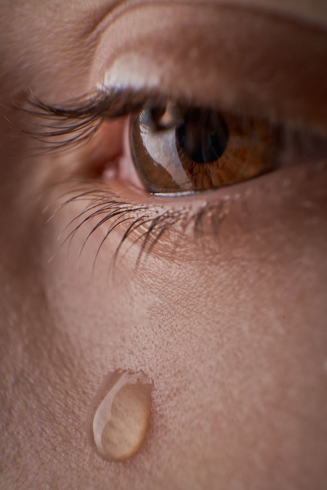 Eye of unrecognizable discontent kid with tear