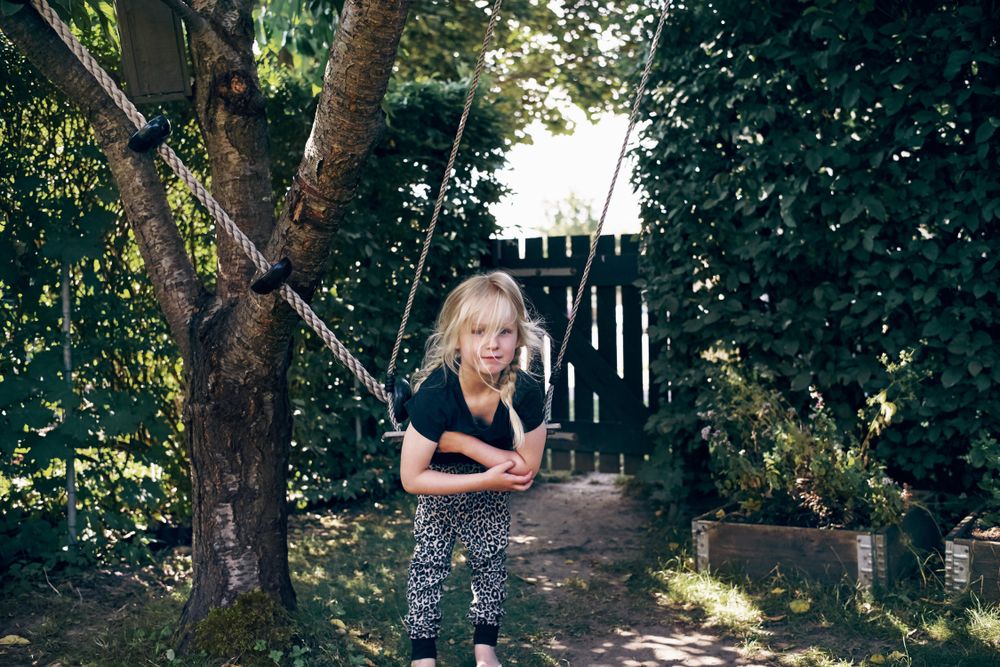 Blonde girl with braided hair leaning on outdoor swing