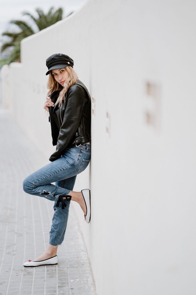 Stylish woman confidently leaning on white wall