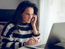 Young female freelancer having phone call and working on