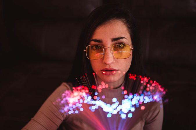 Young woman with fairy lights in darkness