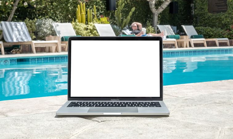 Laptop with blank screen for mock up pool side on sunny day