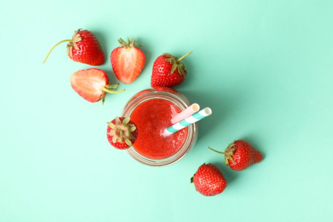Glass jar with strawberry cocktail on mint background. Summer drink