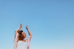 Happy woman raising arms to sky