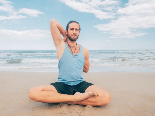 Man training yoga on beach
