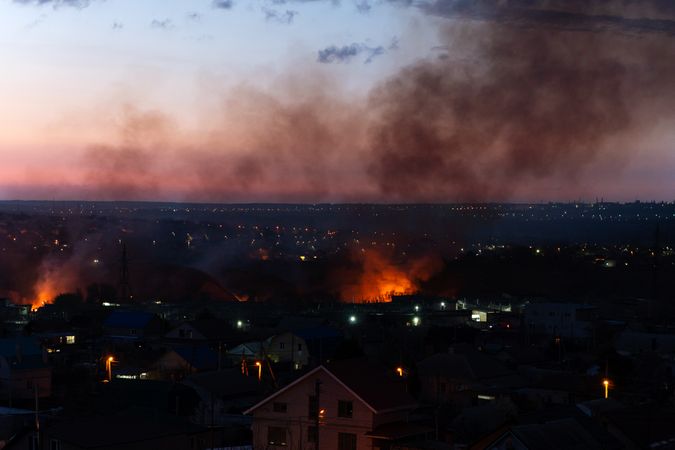 Large-scale fire spreads through suburban residential area at dusk