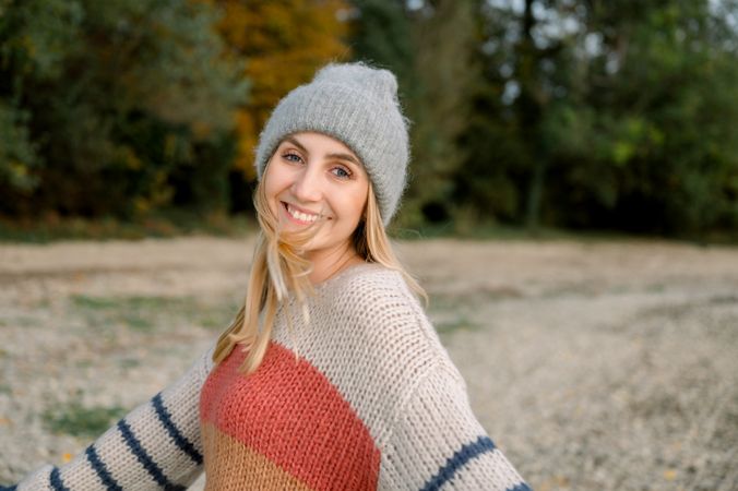 Happy woman with arms outstretched wearing knitwear and hat