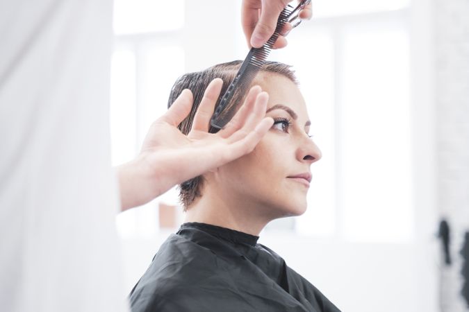 Hairdresser cuts woman's hair with scissors