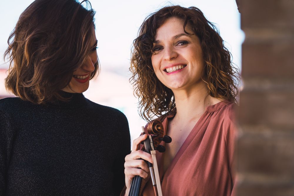 Young smiling women with violin on balcony
