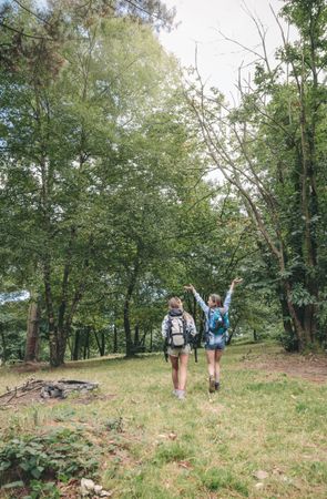Hiker raising arms and enjoying walk with friend
