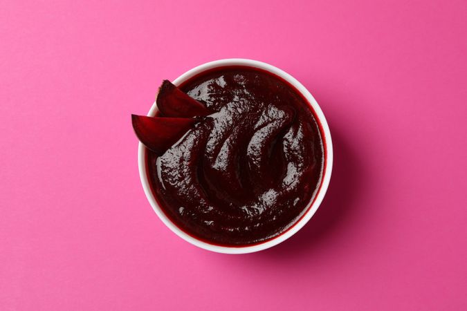 Looking down at bowl of borscht or beetroot soup on pink table