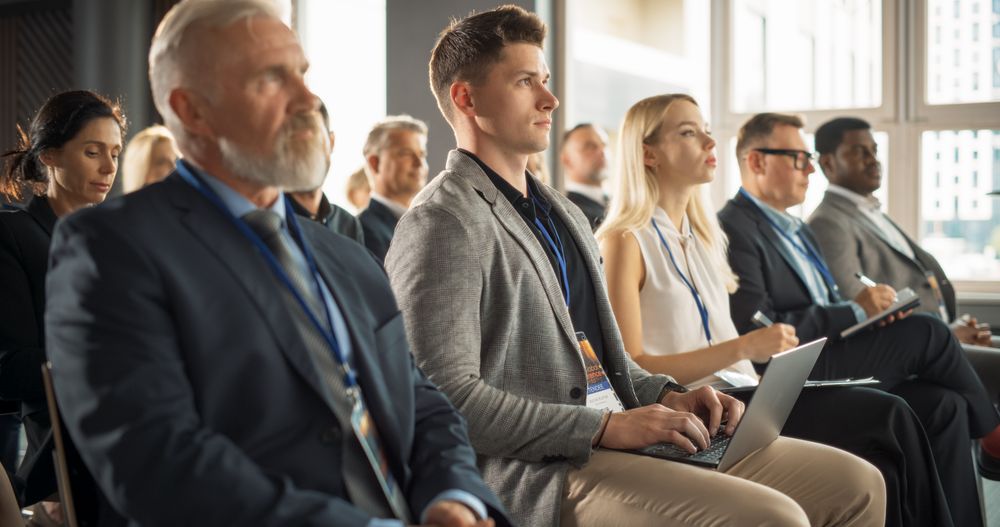 Crowd of Smart Businesspeople in Bright Conference Hall Watching an Innovative Inspiring Keynote Presentation Of New Gadget.