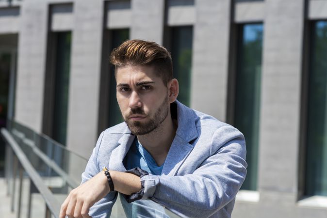 Portrait of man leaning on railings outdoor while looking to camera