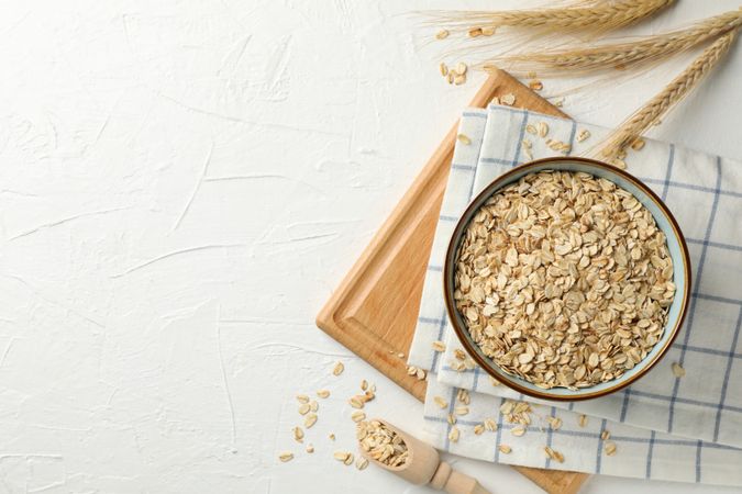 Composition with oatmeal flakes on plain background, top view. Cooking breakfast