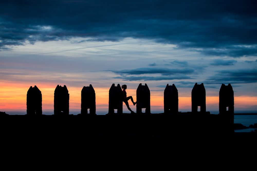 Silhouette of person between stone sculptures in sunset
