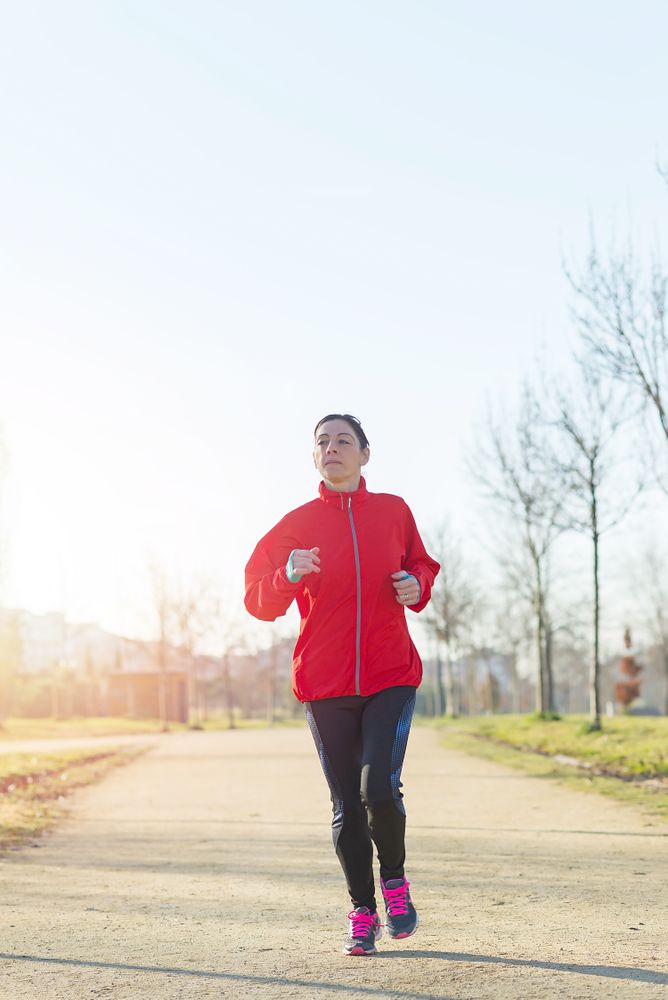 Woman running outdoors in a park on sunny day
