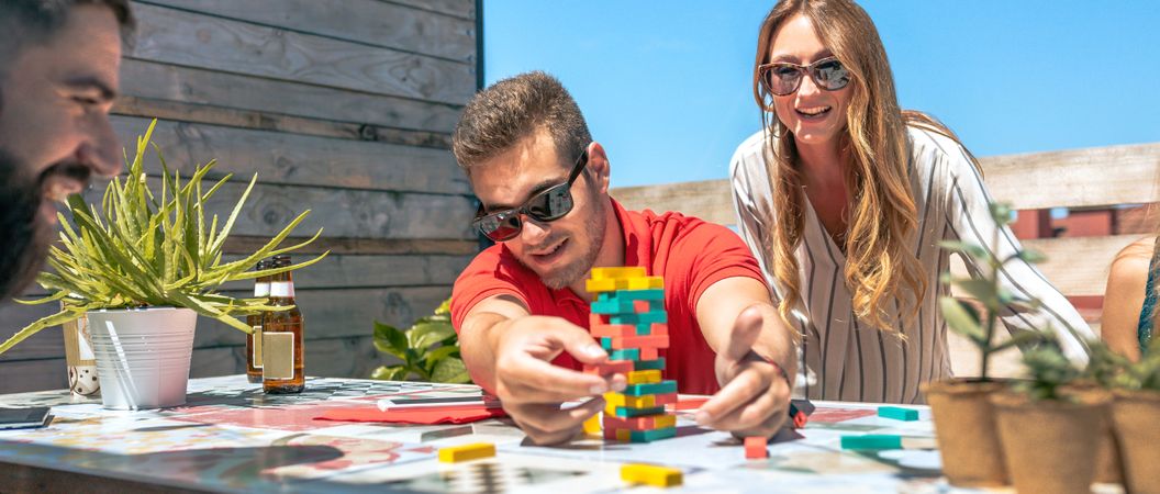 Concentrated man catching game piece next to colleagues on terrace