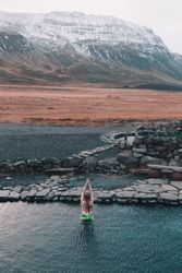 Woman in water near stones and hill