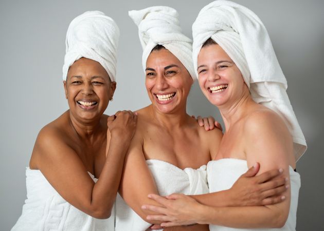 Cheerful multiracial women hugging during spa session