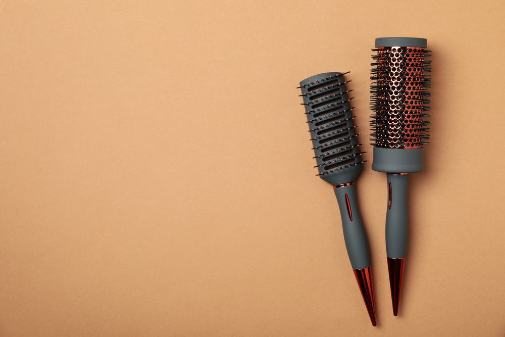 Hair brushes on brown background, space for text